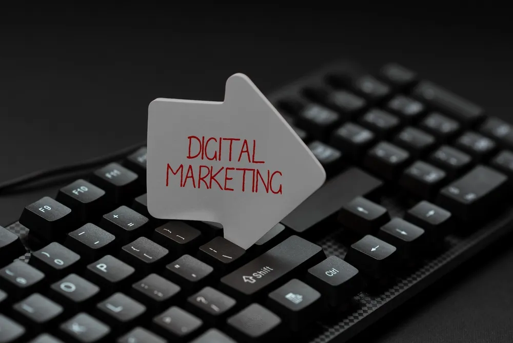 Une flèche sur laquelle est écrit "digital marketing" posée sur un clavier d'ordinateur noir